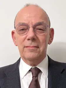 Man in suit with glasses against white background.